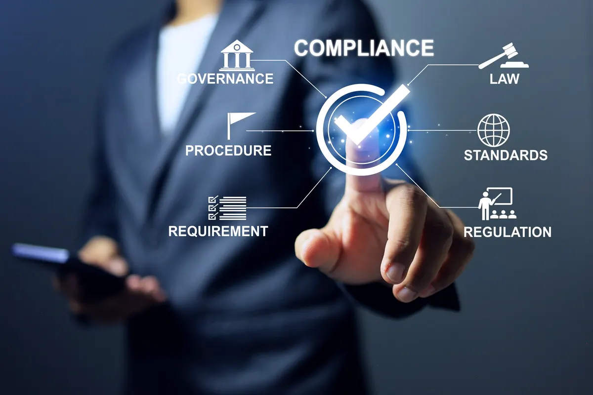 A man in a dark suit reaching towards a glowing tick inside a circle, with lines running out to icons labelled governance, law, procedure, standards, requirement and regulation